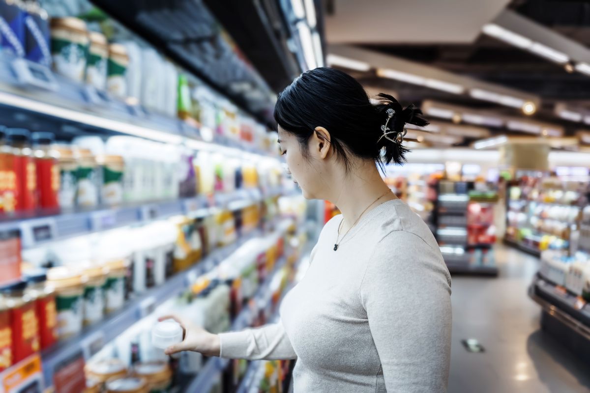 Woman shopping for groceries in the cold foods section.